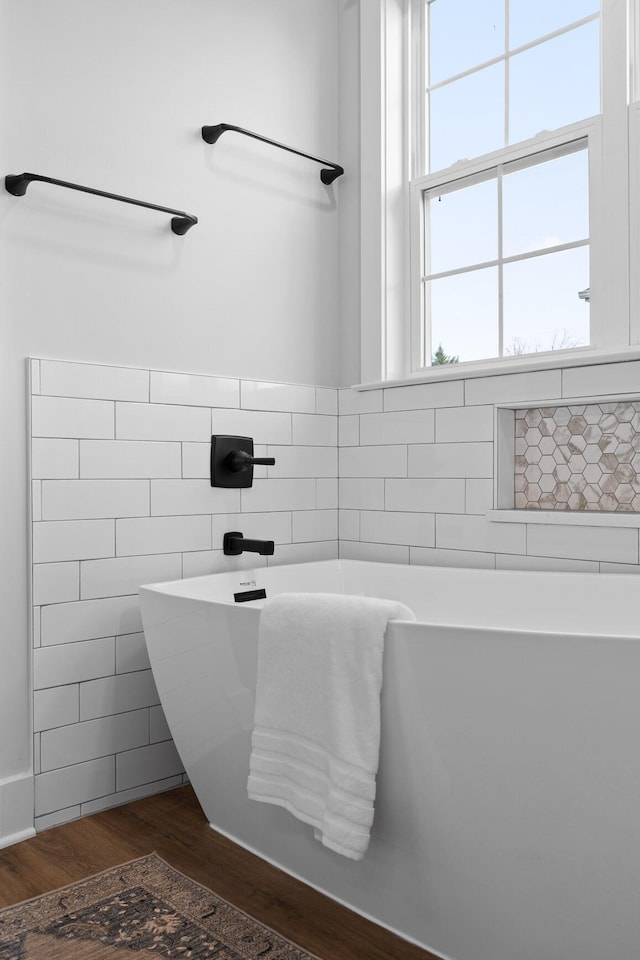 bathroom with a washtub and hardwood / wood-style flooring