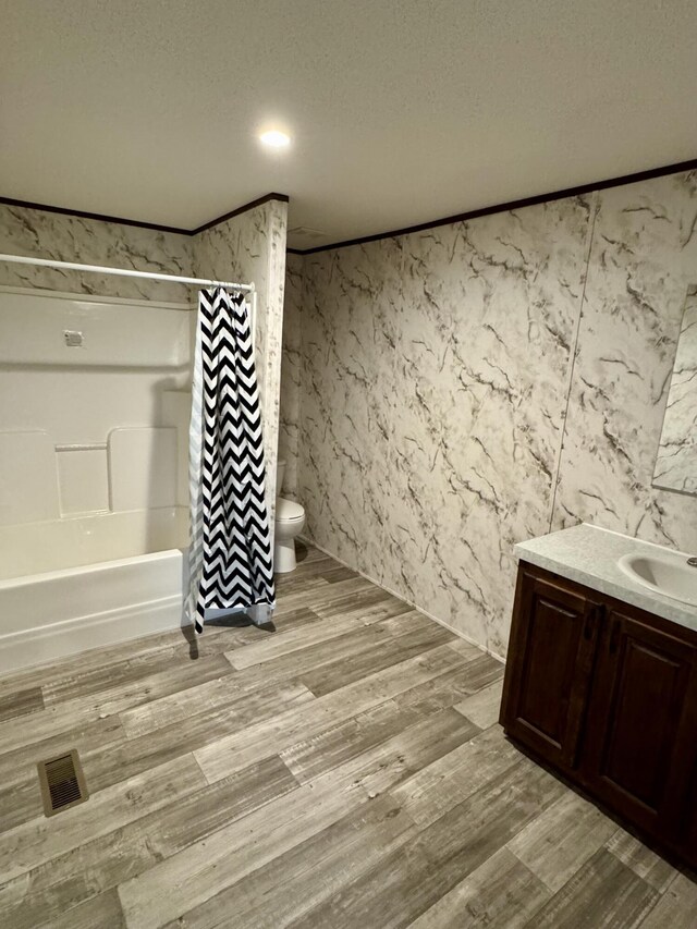 full bathroom with toilet, shower / bathtub combination with curtain, a textured ceiling, and wood finished floors