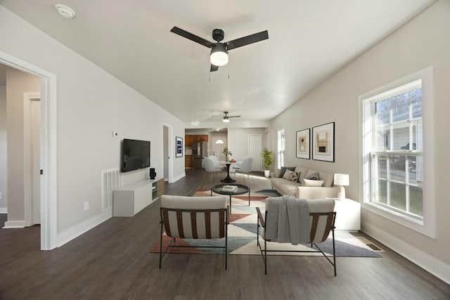 living room with plenty of natural light, dark wood-type flooring, and ceiling fan