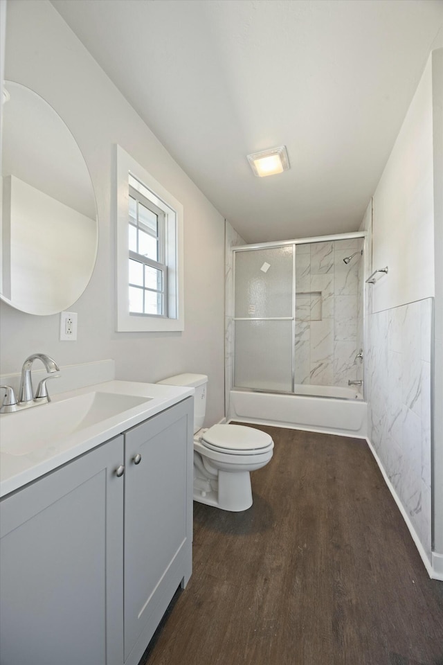 full bathroom with tiled shower / bath, toilet, vanity, and hardwood / wood-style flooring