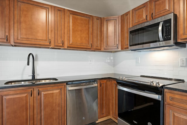 kitchen featuring decorative backsplash, dark stone countertops, sink, and appliances with stainless steel finishes