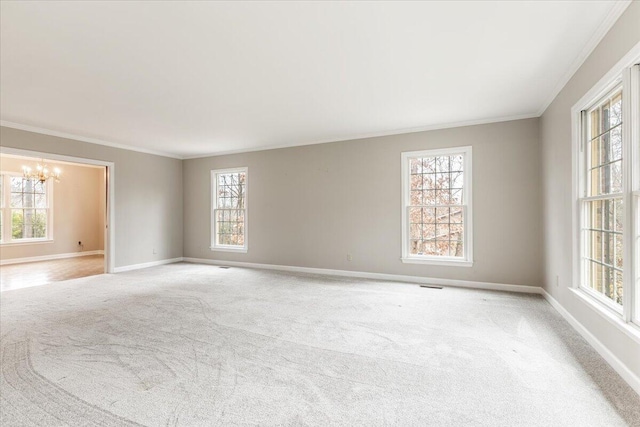 empty room with a chandelier, a wealth of natural light, and crown molding