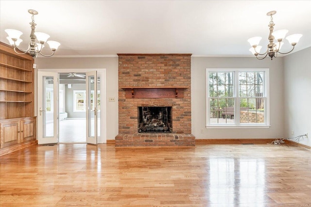 unfurnished living room featuring light hardwood / wood-style flooring, crown molding, a fireplace, and a chandelier