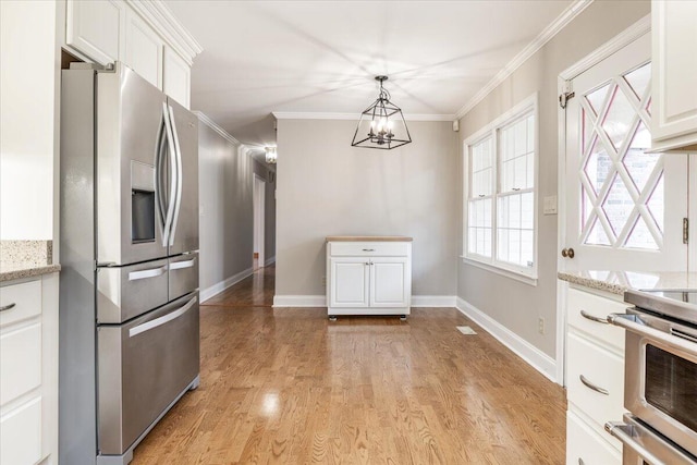 kitchen with an inviting chandelier, light stone counters, stainless steel refrigerator with ice dispenser, white cabinets, and range