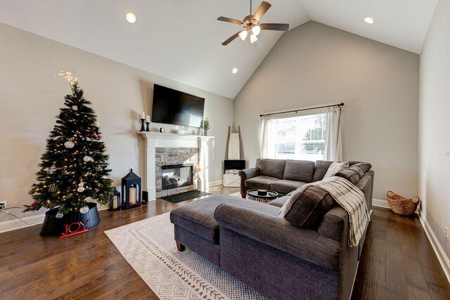 living room with dark hardwood / wood-style flooring, ceiling fan, a fireplace, and high vaulted ceiling