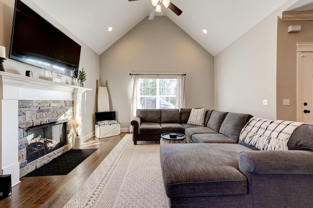 living room with a stone fireplace, ceiling fan, lofted ceiling, and hardwood / wood-style flooring