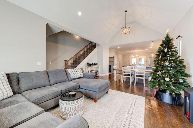 living room featuring dark wood-type flooring, lofted ceiling, and a notable chandelier