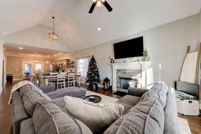 living room featuring vaulted ceiling, a fireplace, ceiling fan with notable chandelier, and dark hardwood / wood-style floors