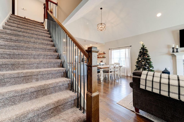 stairs featuring a chandelier, hardwood / wood-style floors, and a towering ceiling