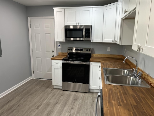 kitchen featuring sink, white cabinetry, stainless steel appliances, and wooden counters