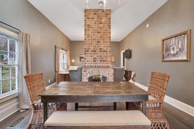 dining room featuring dark hardwood / wood-style floors, lofted ceiling, and a fireplace