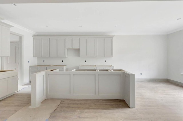 laundry room with ornamental molding and light hardwood / wood-style flooring