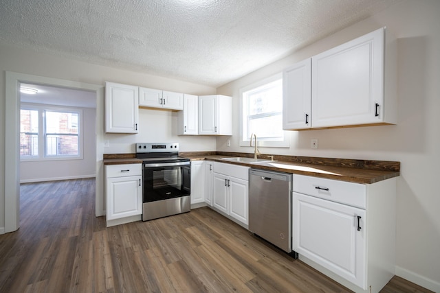 kitchen with dark wood-type flooring, sink, a textured ceiling, appliances with stainless steel finishes, and white cabinetry