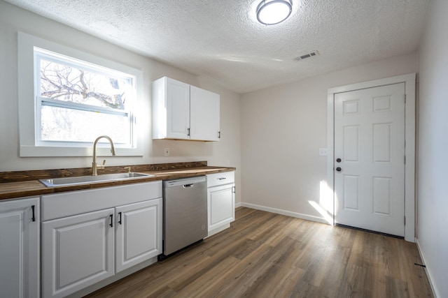 kitchen featuring butcher block countertops, white cabinetry, dishwasher, and sink