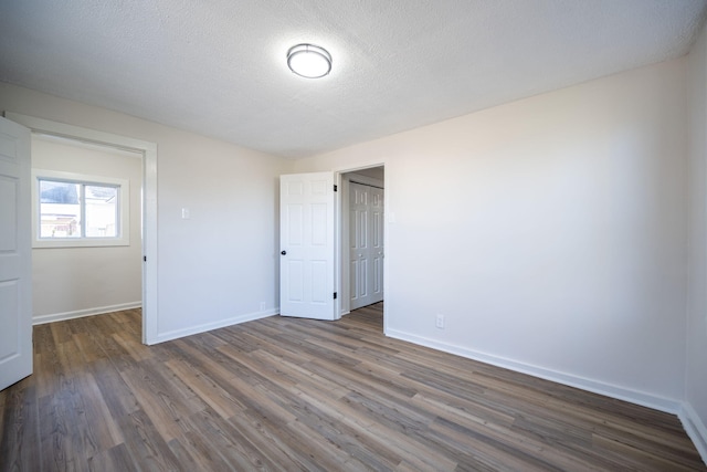 unfurnished room featuring a textured ceiling and dark hardwood / wood-style flooring