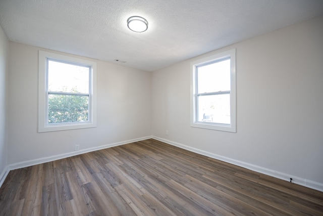 unfurnished room featuring a textured ceiling and dark hardwood / wood-style flooring