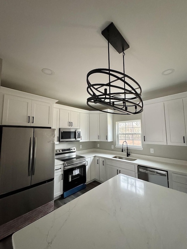 kitchen with sink, white cabinetry, stainless steel appliances, dark hardwood / wood-style flooring, and decorative light fixtures