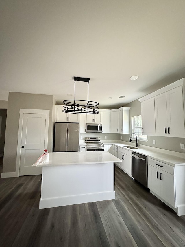 kitchen with sink, appliances with stainless steel finishes, white cabinetry, hanging light fixtures, and a center island