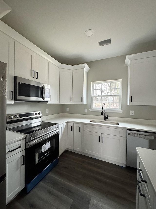 kitchen featuring white cabinetry, appliances with stainless steel finishes, sink, and dark hardwood / wood-style flooring