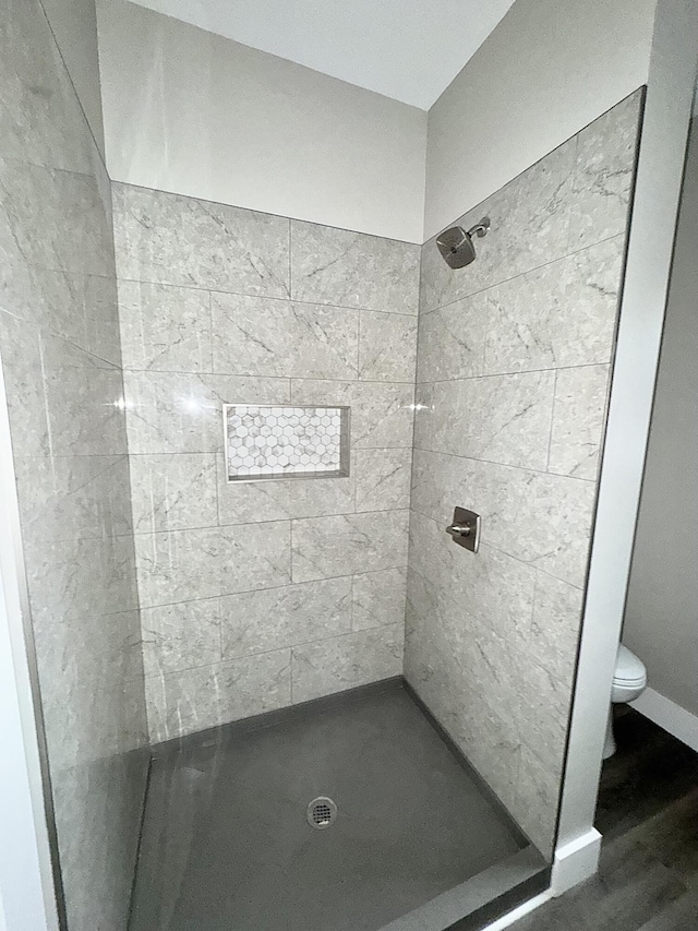 bathroom featuring tiled shower, toilet, and hardwood / wood-style floors