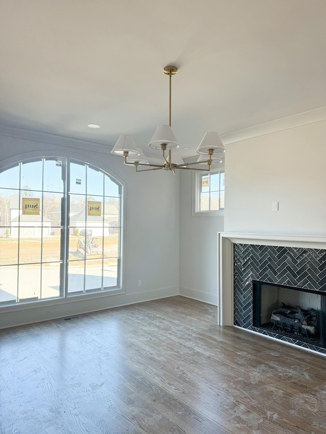 unfurnished living room featuring wood-type flooring, crown molding, and a tiled fireplace