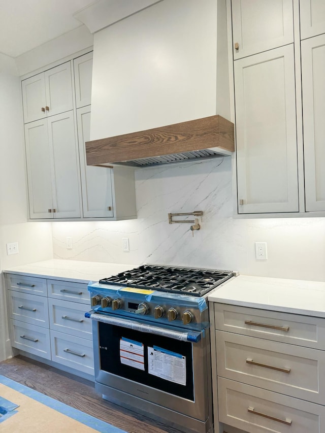 kitchen with high end range, backsplash, gray cabinets, dark hardwood / wood-style flooring, and custom range hood