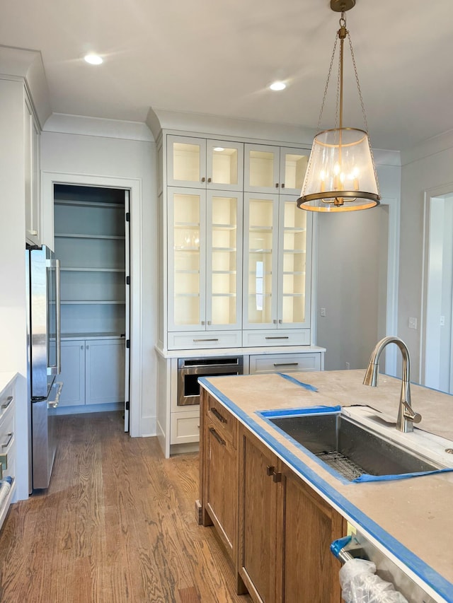 kitchen featuring appliances with stainless steel finishes, sink, pendant lighting, an inviting chandelier, and white cabinetry