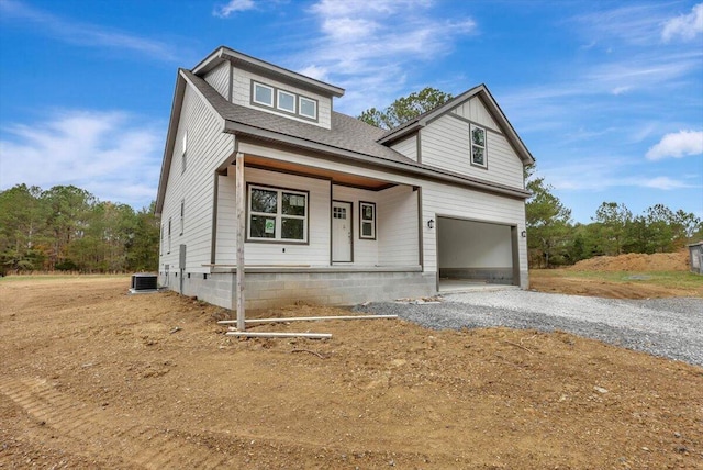 view of front of home with central air condition unit, covered porch, and a garage