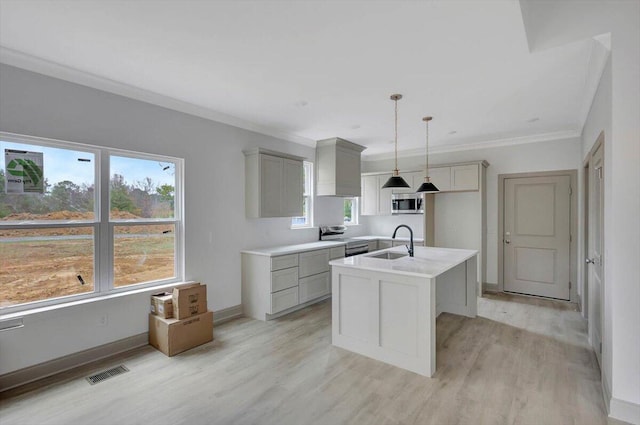 kitchen featuring a center island with sink, sink, hanging light fixtures, gray cabinets, and appliances with stainless steel finishes