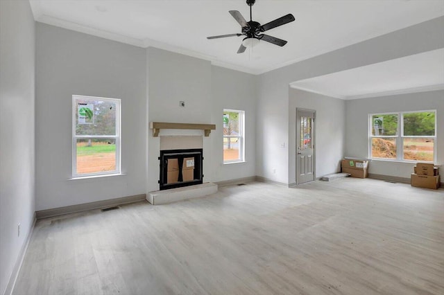 unfurnished living room with a wealth of natural light, ceiling fan, and ornamental molding