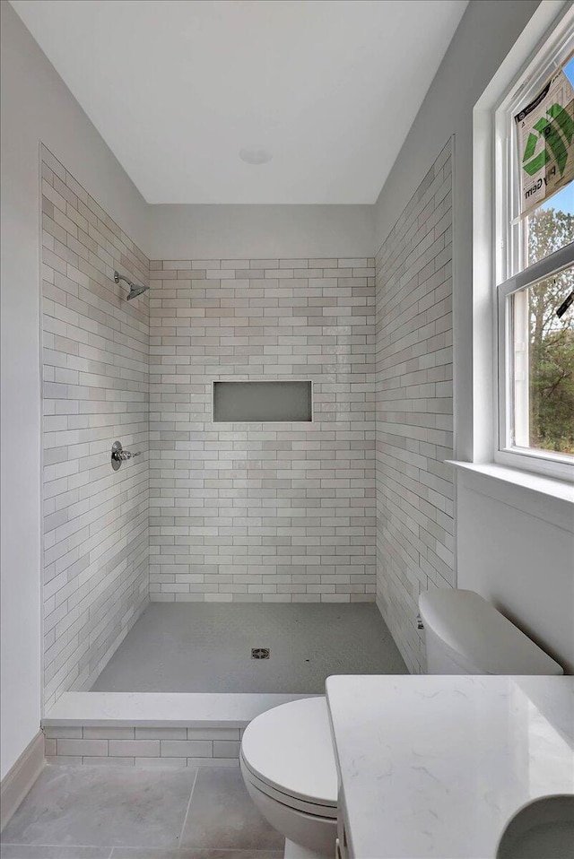 bathroom with vanity, toilet, and a tile shower