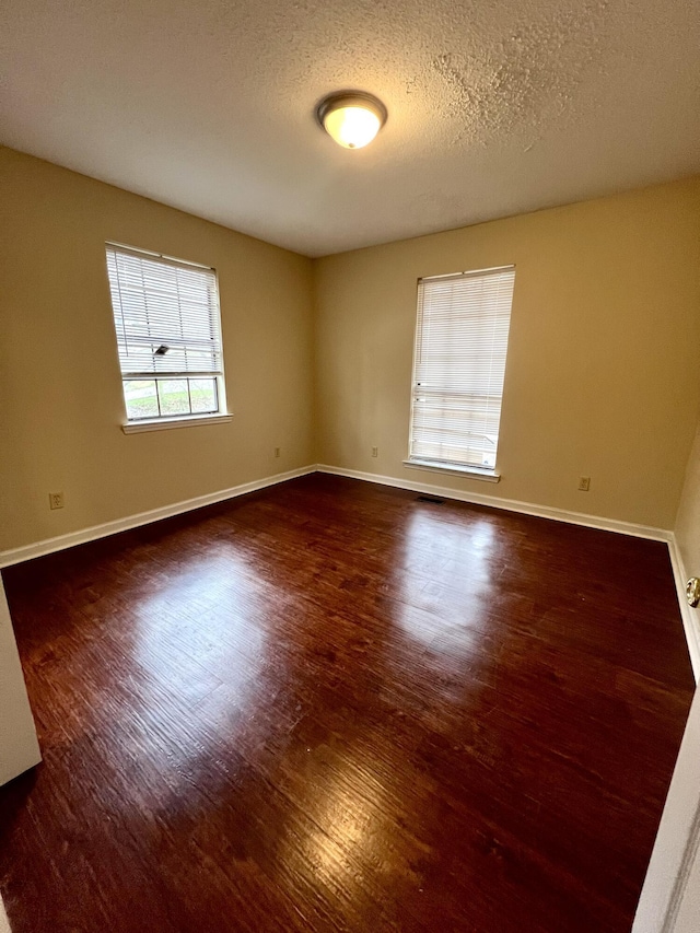 spare room with dark wood-type flooring and a textured ceiling