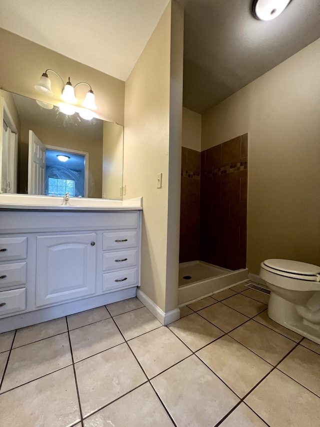 bathroom with vanity, toilet, tile patterned flooring, and a tile shower