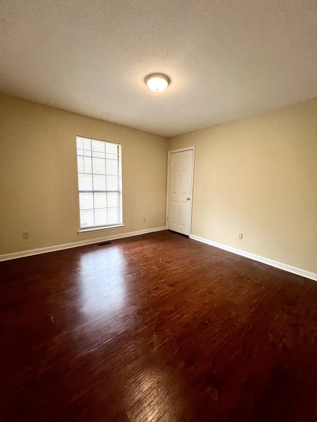 unfurnished room featuring dark hardwood / wood-style flooring and a textured ceiling