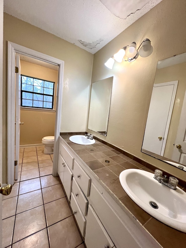 bathroom featuring tile patterned flooring, vanity, a textured ceiling, and toilet