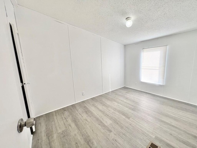 spare room featuring light hardwood / wood-style flooring and a textured ceiling