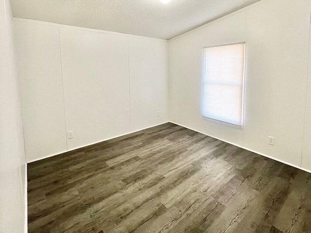 spare room with dark hardwood / wood-style floors and a textured ceiling