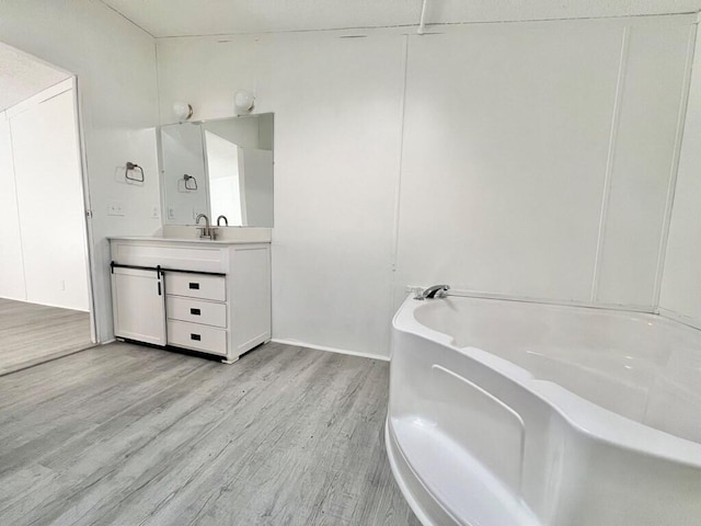 bathroom with a bath, vanity, and wood-type flooring