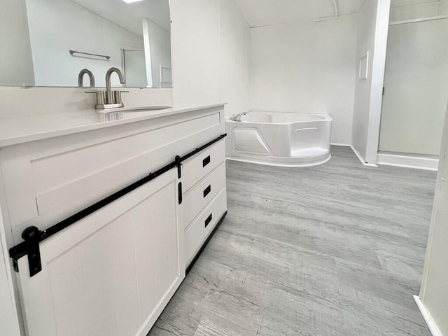 bathroom with hardwood / wood-style floors, vanity, and separate shower and tub