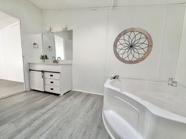 bathroom with vanity, wood-type flooring, and a tub