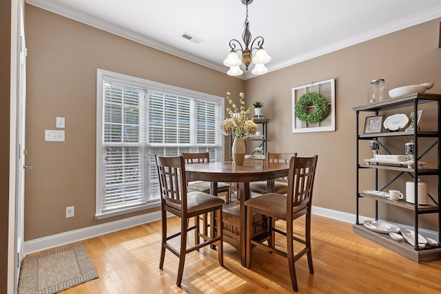 dining room featuring crown molding, light hardwood / wood-style flooring, and an inviting chandelier