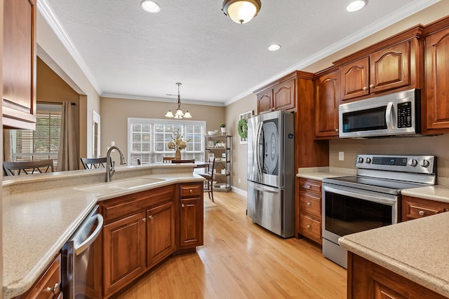 kitchen featuring stainless steel appliances, crown molding, sink, an inviting chandelier, and hanging light fixtures