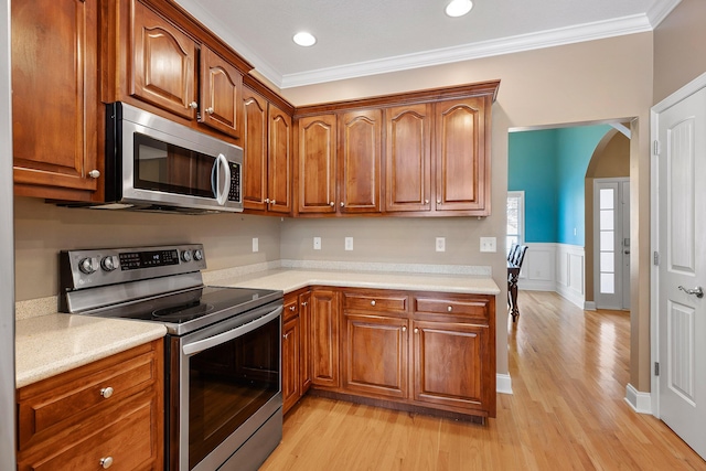 kitchen featuring light hardwood / wood-style floors, ornamental molding, and appliances with stainless steel finishes