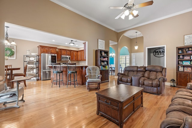 living room featuring ceiling fan with notable chandelier, ornamental molding, and light hardwood / wood-style flooring