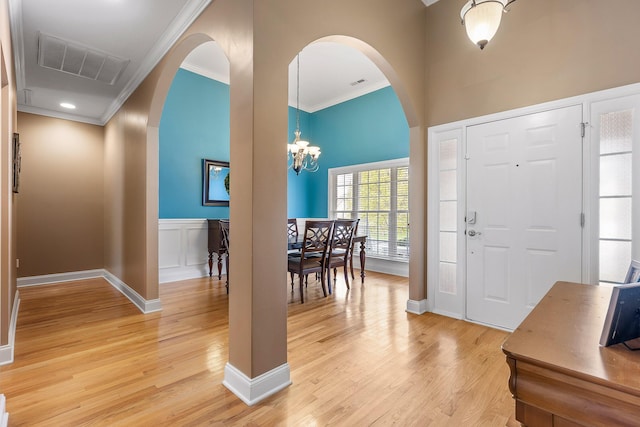 entrance foyer featuring a notable chandelier, light wood-type flooring, and crown molding