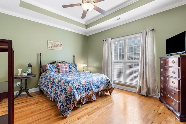 bedroom featuring ceiling fan, light hardwood / wood-style flooring, crown molding, and a tray ceiling