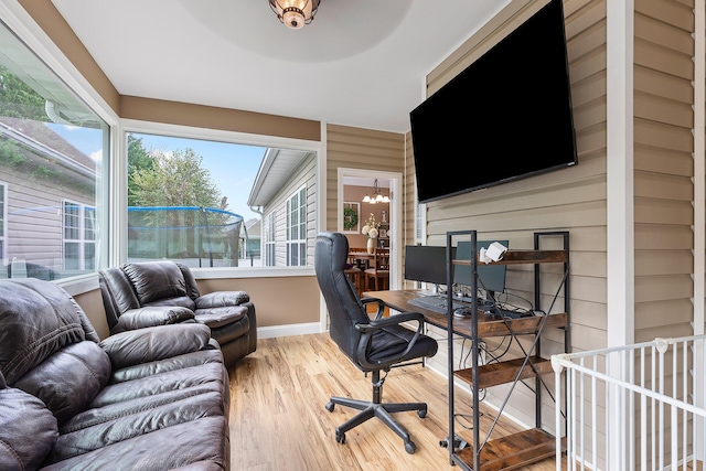 office area with hardwood / wood-style flooring, wooden walls, and a notable chandelier