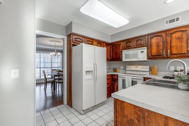 kitchen with white appliances, sink, decorative light fixtures, an inviting chandelier, and light tile patterned flooring