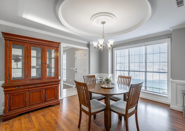 dining area with crown molding, light hardwood / wood-style floors, and an inviting chandelier