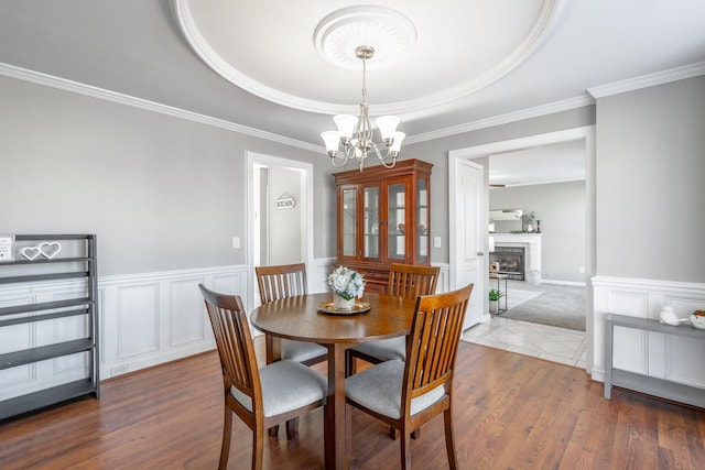 dining room with wood-type flooring, a tray ceiling, an inviting chandelier, and ornamental molding